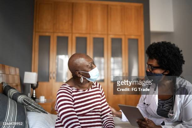 visitatore sanitario e una donna anziana durante la visita alla casa di cura - pandemic illness foto e immagini stock
