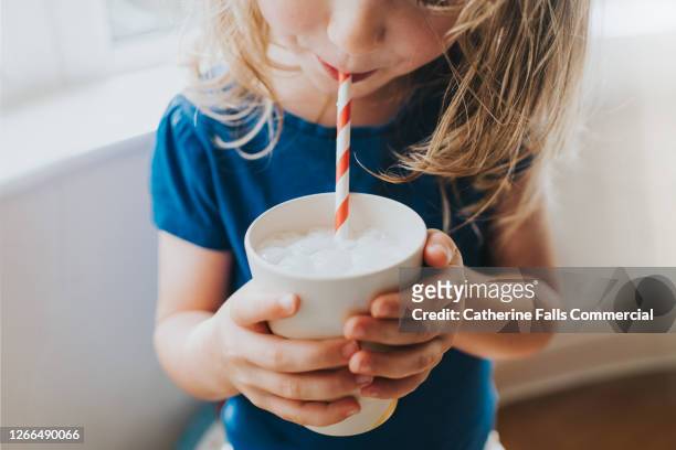 little girl drinking a cup of milk with a paper straw - drink milk stock pictures, royalty-free photos & images