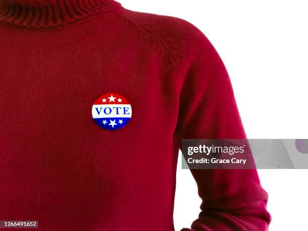 woman in red wears "vote" sticker - voting sticker stock pictures, royalty-free photos & images