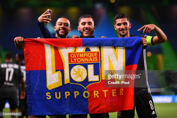 Memphis Depay, Rayan Cherki and Houssem Aouar of Olympique Lyon celebrate with a supporters flag following their team's victory in the UEFA Champions...