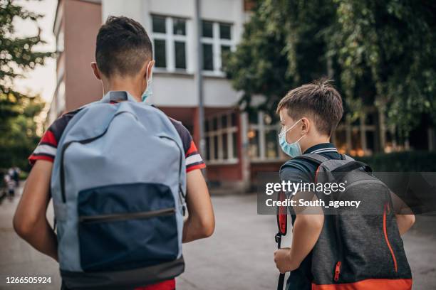 two schoolboys with surgical masks going to school - safe kids day arrivals stock pictures, royalty-free photos & images