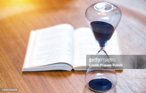 stack of colorful books with hourglass on top. reading time concept - hourglass books fotografías e imágenes de stock