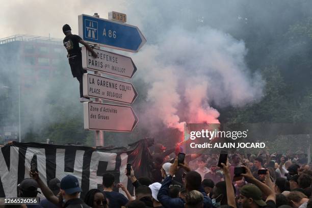 Attendee stands atop a street sign during a commemoration march for Nahel, a teenage driver shot dead by a policeman, in the Parisian suburb of...