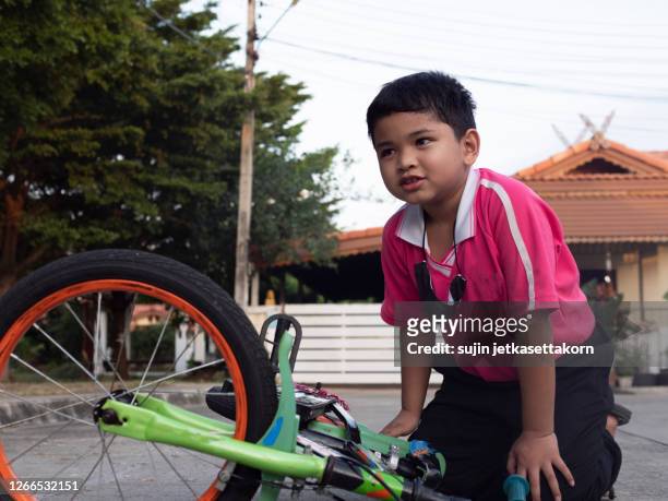 asian kid students exercise bicycle outdoor in front of the village - boy thailand stock-fotos und bilder