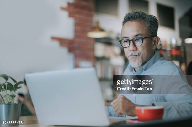 an asian chinese senior man having discussion with his colleague via online virtual meeting in a cafe - asiático e indiano imagens e fotografias de stock
