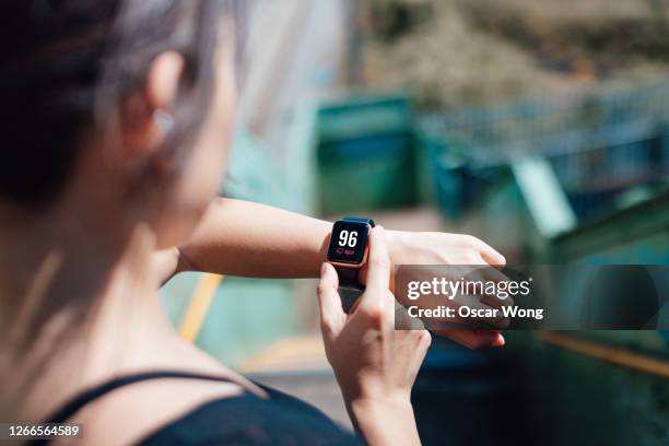 young woman checking heart rate on smart watch - reloj inteligente fotografías e imágenes de stock