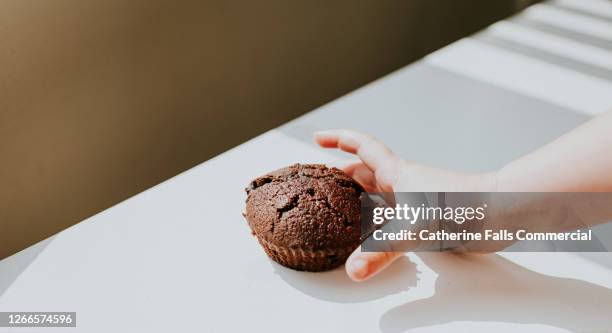 child's hand reaching for a chocolate chip bun - hand child stock pictures, royalty-free photos & images