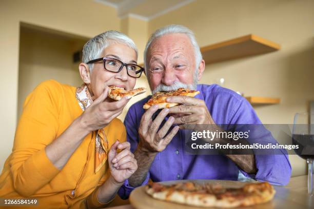 an older man and his lovely wife are enjoying in pizza and wine. - comer pizza imagens e fotografias de stock