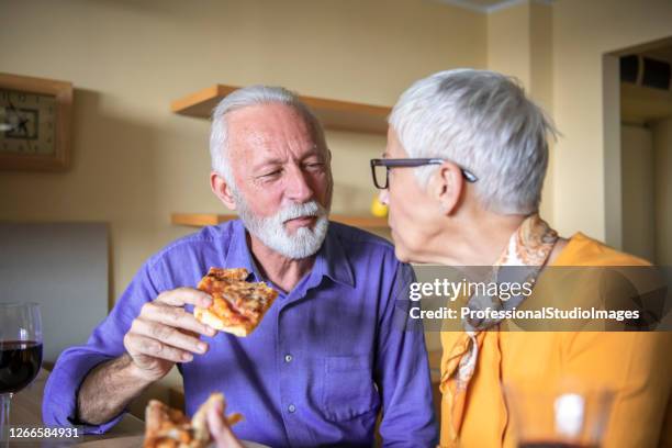 handsome older man and his beautiful wife are eating tasty pizza. - cheese pizza stock pictures, royalty-free photos & images
