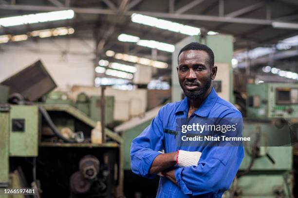 african american maintenance worker standing with arm crossed. he working in heavy industry, wearing mechanic jumpsuit, coveralls. - black jumpsuit stock-fotos und bilder