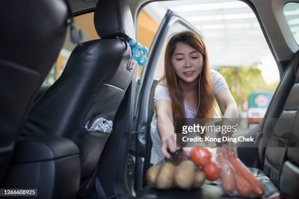 de chinese vrouw van azië kocht alle kruidenierswaren van supermarkt en zettend in auto. - chinese car home stockfoto's en -beelden