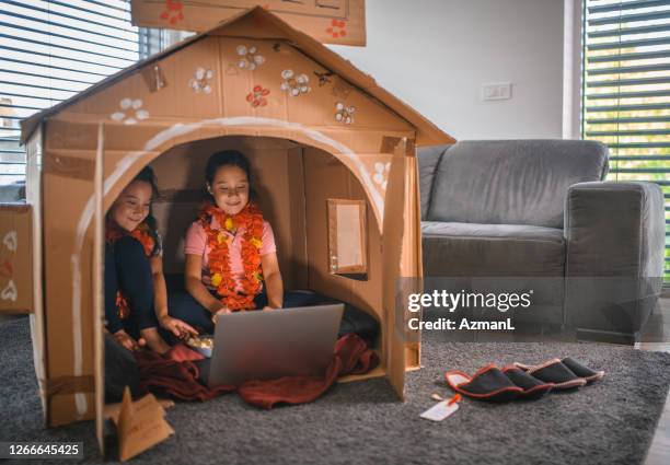 asiatische schwestern sehen film in pappe haus während der quarantänezeit - playhouse stock-fotos und bilder