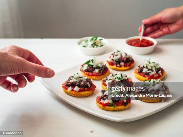 two person serving themselves "sopes" also known as "picadita", traditional mexican dish on a white background - avocado toast white background stockfoto's en -beelden