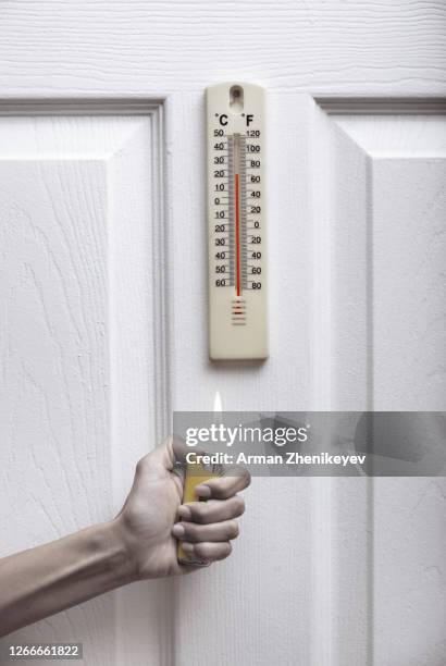 human hands holding lighter under the indoors termometer - flint new york screening stock pictures, royalty-free photos & images