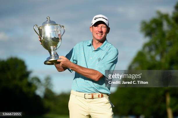 Jim Herman of the United States celebrates with the trophy on the 18th green after winning during the final round of the Wyndham Championship at...