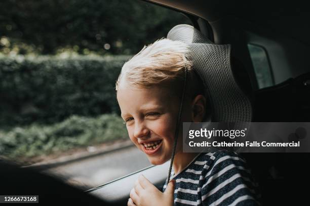 child enjoying the wind blowing through his hair in the back seat of a car - anticipation excited stock pictures, royalty-free photos & images