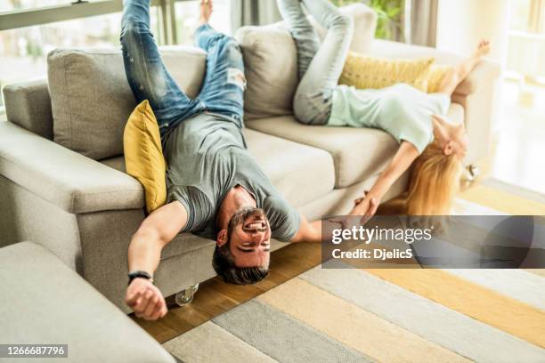 ecstatic couple having fun in the living room and laughing. - upside down stock pictures, royalty-free photos & images