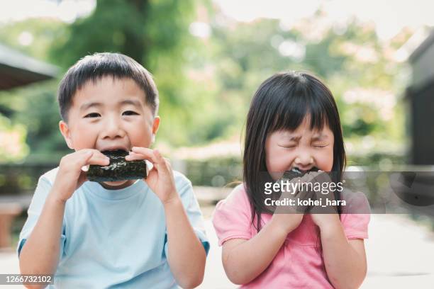 broer of zus die een rijstbal in openlucht eet - quirky family stockfoto's en -beelden