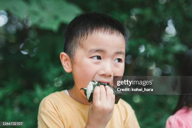 jongen die een rijstbal in openlucht eet - rice ball stockfoto's en -beelden