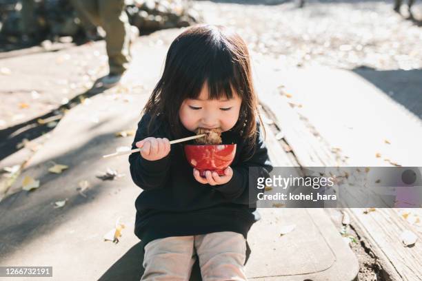 mädchen essen reiskuchen im park - mochi stock-fotos und bilder