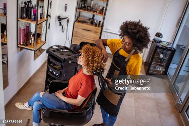 friseur arbeitet im schönheitssalon - afro hairstyle stock-fotos und bilder