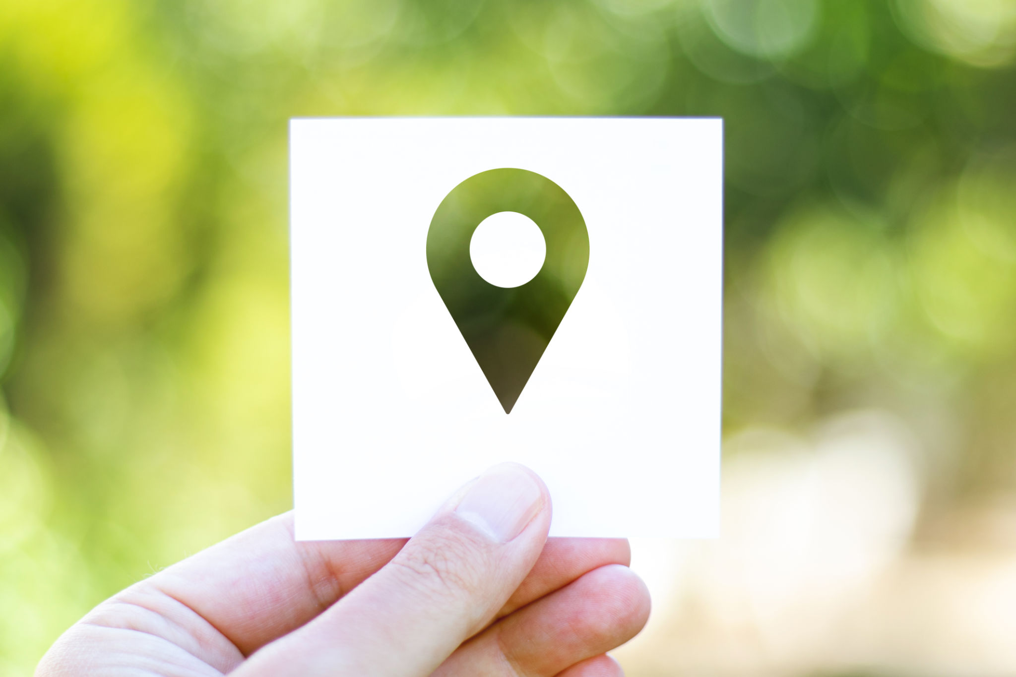 Holding the paper with Pin Icon in front of a beautiful blur nature background Holding the paper with Pin Icon in front of a beautiful blur nature background