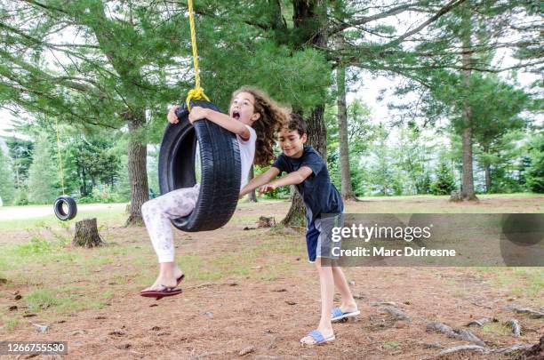 boy helping sister in a swing - tyre swing stock pictures, royalty-free photos & images