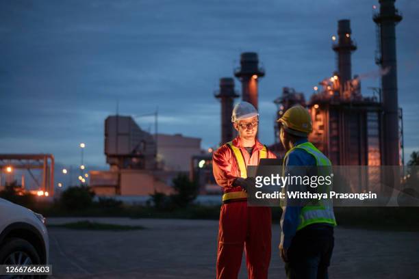 engineer using digital tablet working late night shift at petroleum oil refinery in industrial - oil and gas workers stock-fotos und bilder