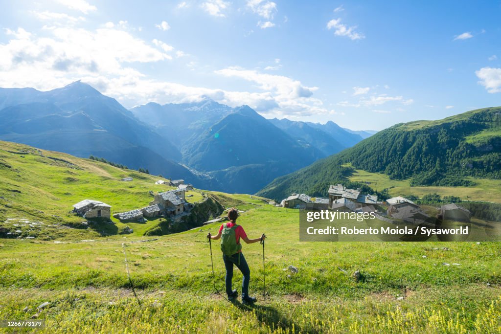 Woman admiring the alpine village, Toiana, Valtellina, Italy