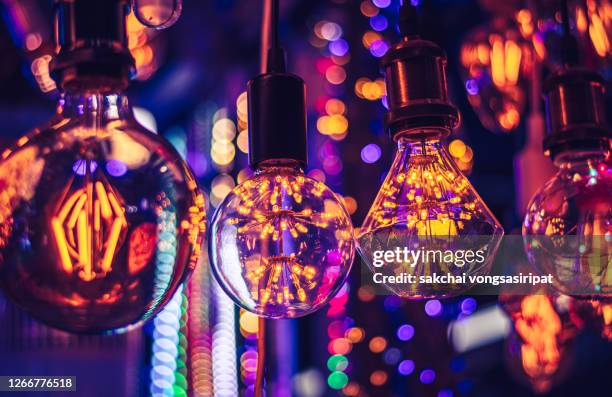 close-up of illuminated light bulbs hanging from ceiling - light party ストックフォトと画像