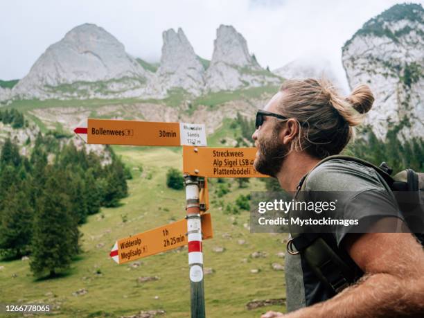 wanderer schaut auf richtungsschilder - wegweiser schweiz stock-fotos und bilder