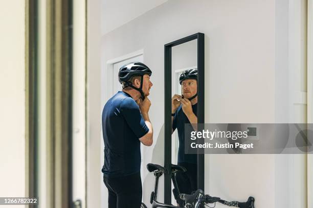cyclist getting ready. he puts his helmet on in the mirror - effet miroir homme photos et images de collection