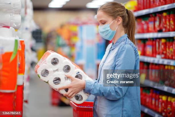 woman readinh label on toilete paper pacakage amid covid-19 pandemia - buying toilet paper stock pictures, royalty-free photos & images