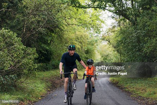 young girl and her father are out cycling in the country side. - steep hill stock pictures, royalty-free photos & images