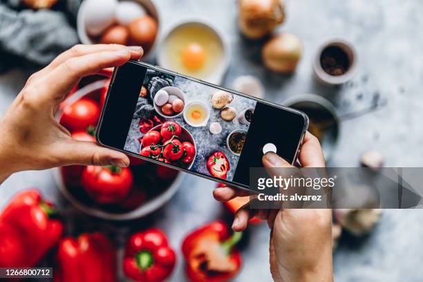 frau fotografiert eine zutatenaufe auf küchentheke - woman cooking phone stock-fotos und bilder