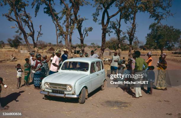 Voiture 'Renault 4L' entourée de curieux dans la région de Tambacounda, en janvier 1974, Sénégal.