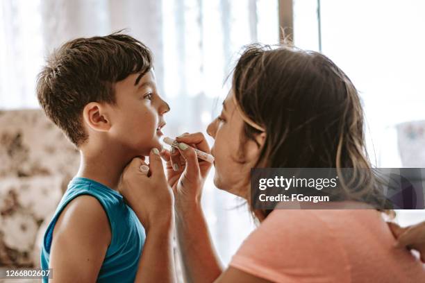 mommy is doing face painting for her son - kids makeup face stock pictures, royalty-free photos & images