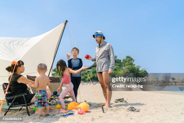 family enjoying their time in nature at beach - japanese tents stock pictures, royalty-free photos & images