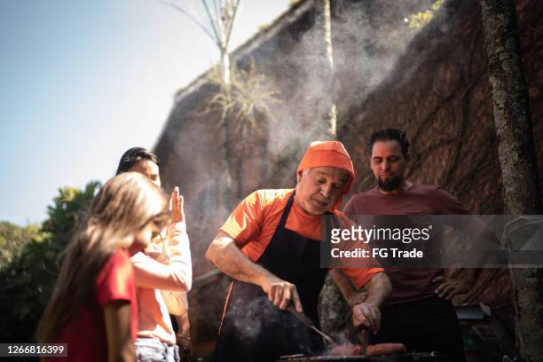 nonno taglia fette di carne durante un barbecue con la famiglia - sausage sizzle foto e immagini stock