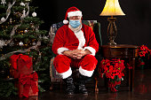 Santa Claus Sitting in a Chair Wearing a Surgical Mask and Looking Towards the Camera