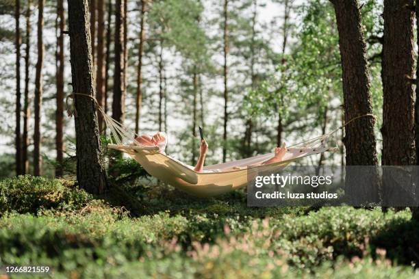 man i en hängmatta läser en bok på en tablett - svensk sommar bildbanksfoton och bilder