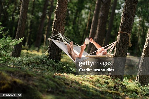 Man in a hammock reading a book on a tablet Man in a hammock reading a book on a tablet