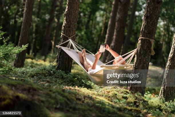 man in a hammock reading a book on a tablet - sweden nature stock pictures, royalty-free photos & images