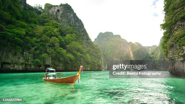 traditional long tail boat on crystal clear water of phi phi island, krabi, thailand. - phi phi islands stock pictures, royalty-free photos & images