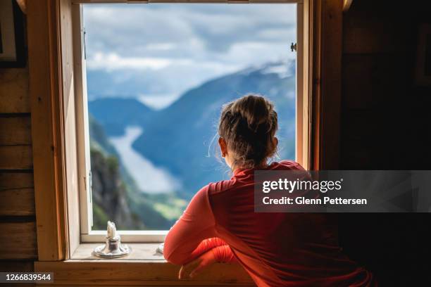 mujer con vistas al fiordo en noruega a través de la ventana. - cabin fotografías e imágenes de stock