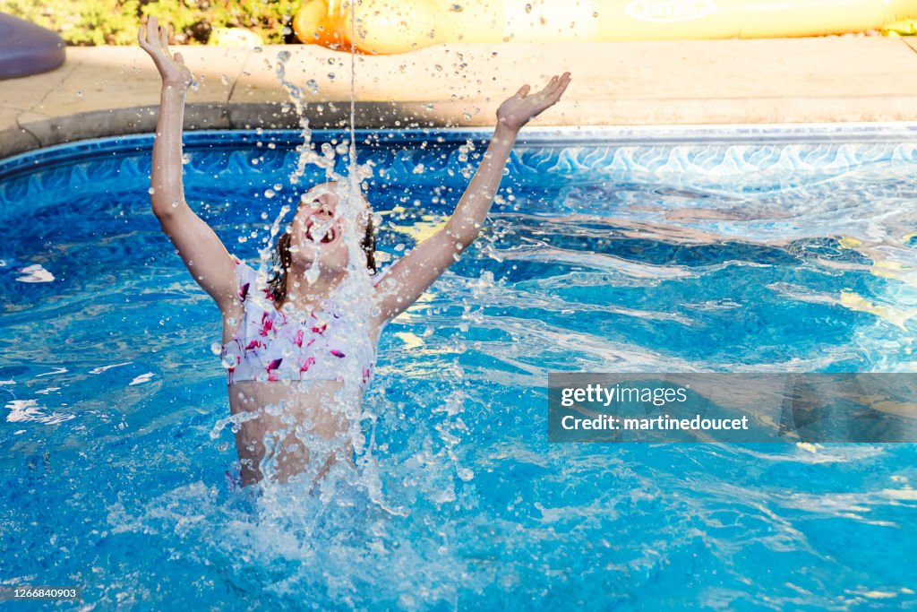 Preteen Mädchen spritzen Wasser im Hinterhof Pool.