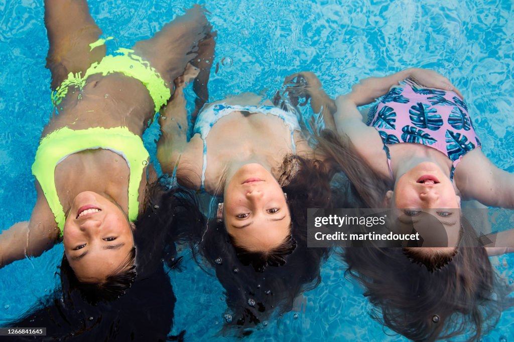 Groep tienermeisjes in pool die zeemeerminnen speelt.