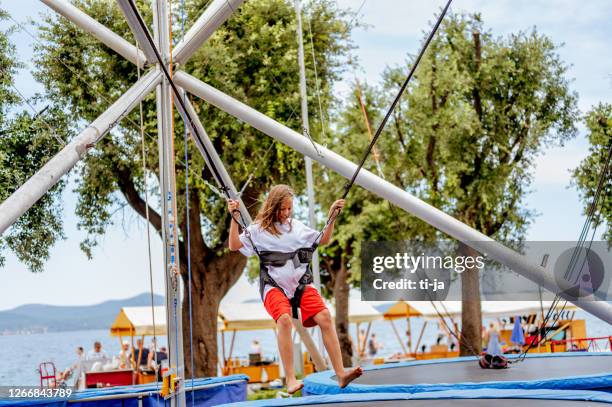 young girl bungee jumping on a trampoline - bungee cord stock pictures, royalty-free photos & images