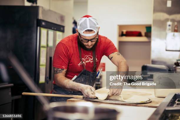 chef preparing pizza in kitchen - pizzeria stock-fotos und bilder