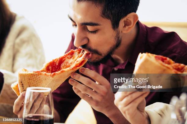 man eating a slice of pizza - pizza fotografías e imágenes de stock